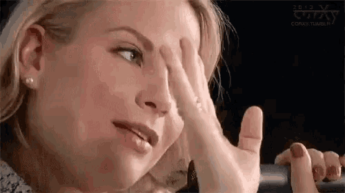 a woman is covering her face with her hand while looking down .