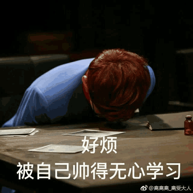 a man with red hair laying his head on a table