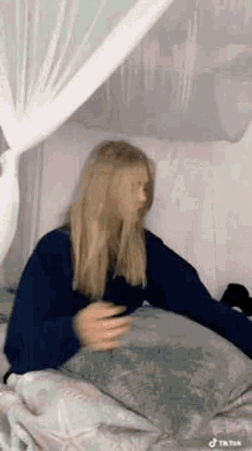 a girl is laying on a bed with a canopy and a pillow .