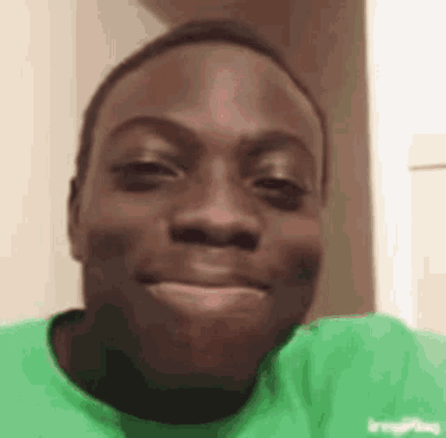 a close up of a man in a green shirt smiling .