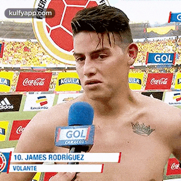 a shirtless soccer player is talking into a microphone in front of a crowd .