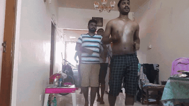 a group of men are dancing in a living room with a barbie table in the background