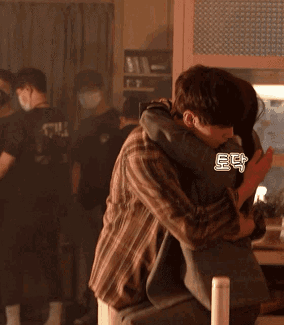 a man in a plaid shirt is hugging another man in a black shirt