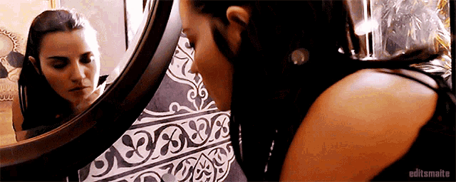 a woman is looking at her reflection in a mirror with editsmalte written on the bottom right