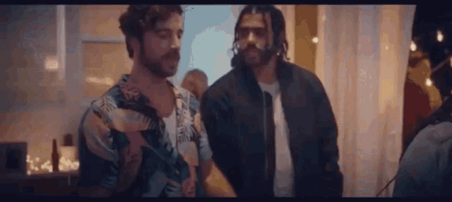 two men are standing next to each other in a room and talking .