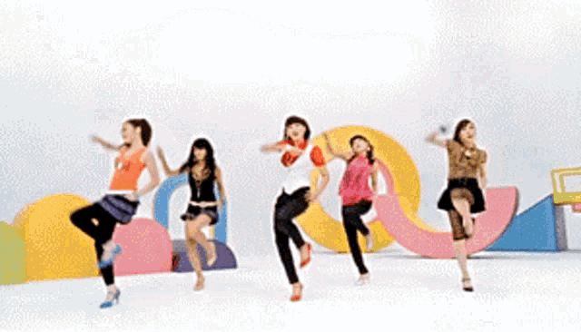 a woman in an orange tank top with a star on it is dancing with other women