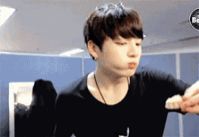 a young man in a black shirt is blowing a kiss .