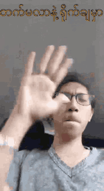 a man wearing glasses is making a funny face with his hand