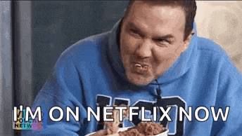 a man in a blue hoodie is eating a bowl of fried chicken .