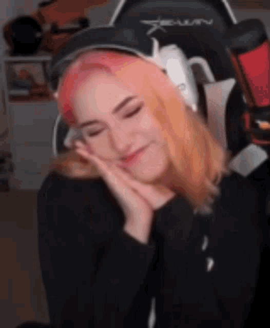 a woman with pink hair is wearing headphones and a hat .