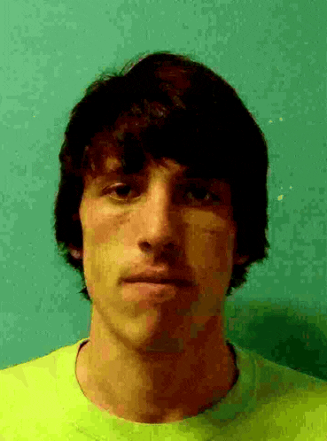 a young man wearing a neon yellow shirt is looking at the camera