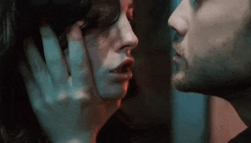 a man and a woman are kissing each other in a dark room