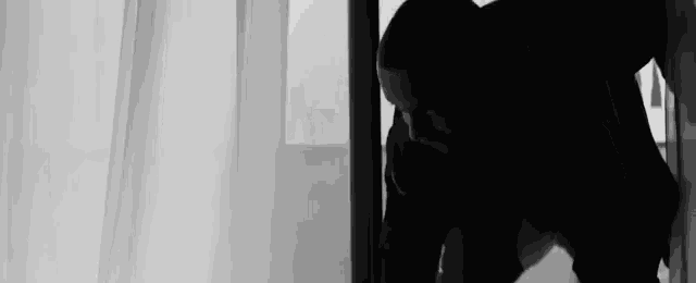 a black and white photo of a man standing in a doorway .
