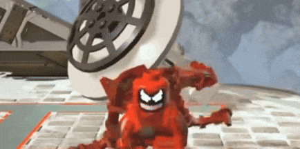 a red lego monster is standing on a brick floor in front of a large wheel .