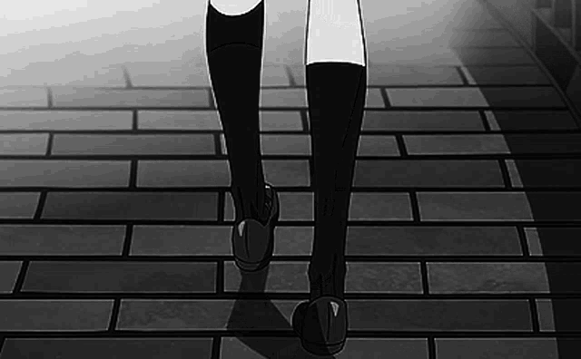 a black and white photo of a person 's feet walking down a brick sidewalk .