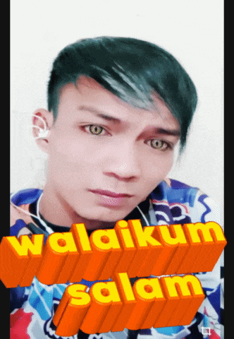 a young man with green hair is wearing ear buds and a shirt that says ' wakilum salam '