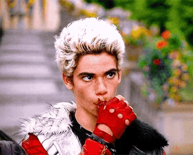 a young man with white hair is wearing red gloves and a fur jacket .