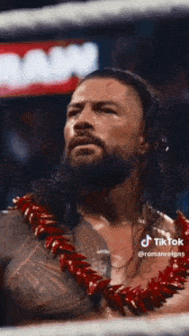roman reigns is wearing a lei and holding a championship belt .