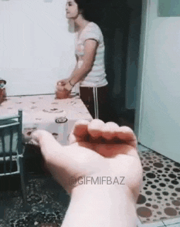 a person is holding a small object in their hand in a living room .