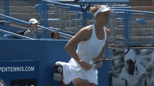 a woman holding a tennis racquet in front of a tennis.com banner