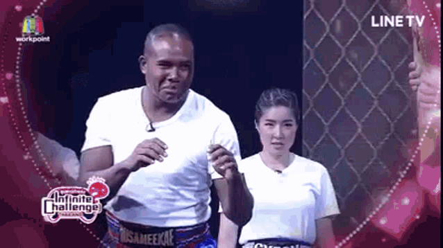a man and a woman are standing next to each other on a stage in front of a fence .