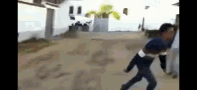 a man is running down a dirt road in front of a white building .
