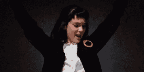 a woman wearing a black jacket and a white shirt is dancing with her arms outstretched .