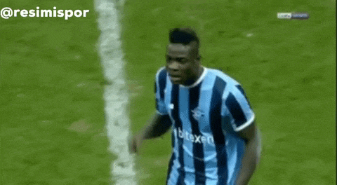 a soccer player in a blue and black striped shirt is standing on the field .