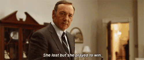 a man in a suit and tie is standing in a living room and saying `` she lost but she played to win . ''