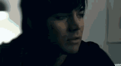 a close up of a man 's face in a dark room looking at something .