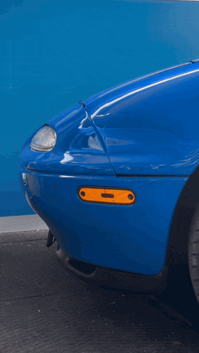 a blue car with the hood up and a hand on it