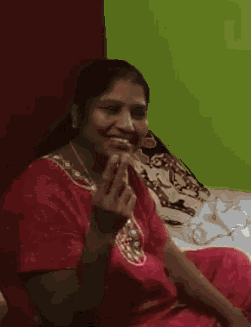 a woman in a red shirt is sitting on a bed