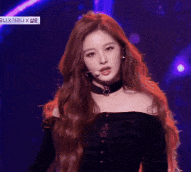 a woman with long red hair wearing a choker and a microphone on stage