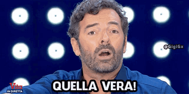 a man with a beard says quella vera in front of a blue background