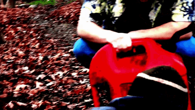 a person is sitting on a red item that says ' fuel can ' on it