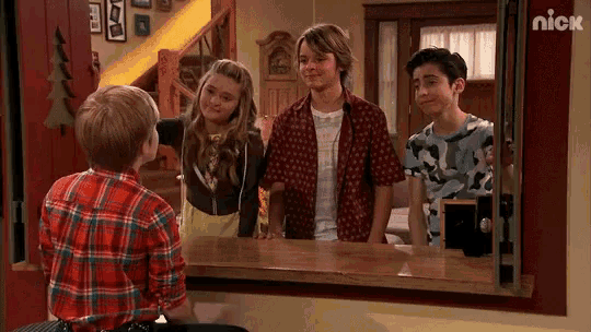 a group of kids are standing in front of a mirror with the nick logo on the wall behind them