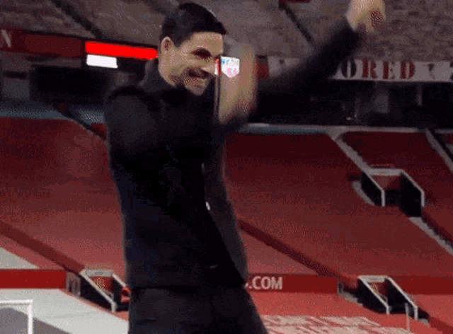 a man in a black suit is dancing in a stadium .