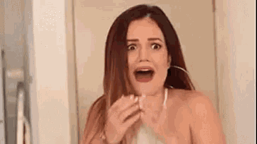 a woman with a surprised look on her face is holding a piece of paper .