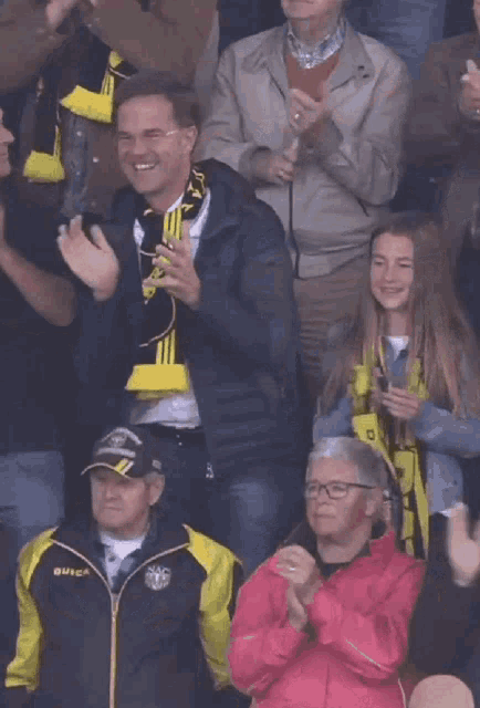 a man wearing a scarf with the letter a on it applauds