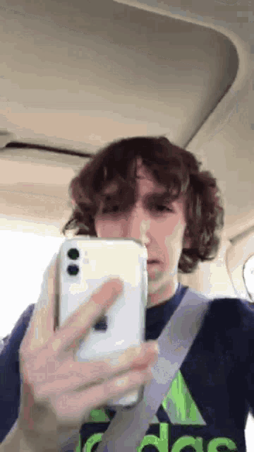 a man in an adidas shirt is taking a picture of himself with his phone