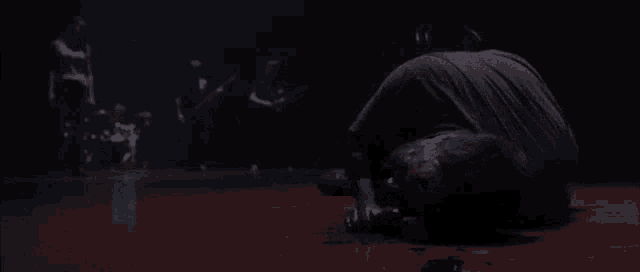 a man is laying on the floor in a dark room with blood on his face .