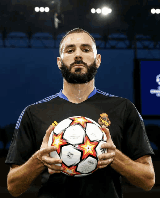 a man with a beard holds a soccer ball in his hands