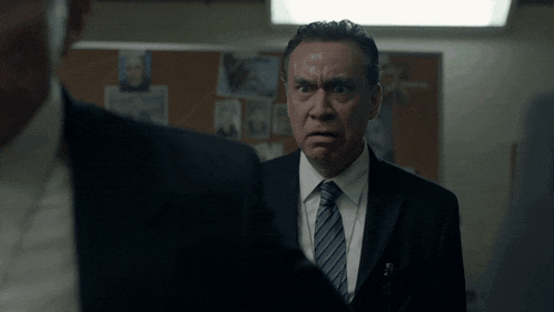 a man in a suit and tie looks at another man in a suit