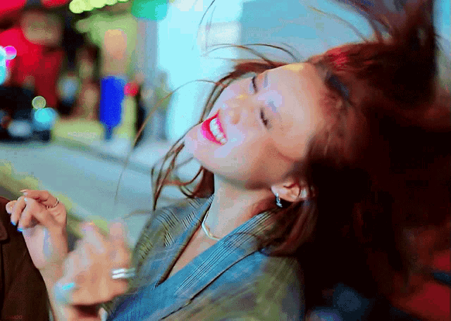 a woman with red lipstick is smiling and her hair is blowing in the wind