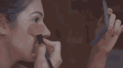 a woman is applying mascara to her eyelashes in a close up .