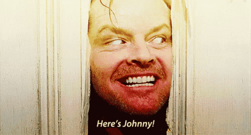 a man is smiling and saying here 's johnny behind a door