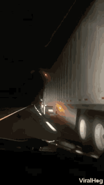 a white semi truck is driving down a highway at night .