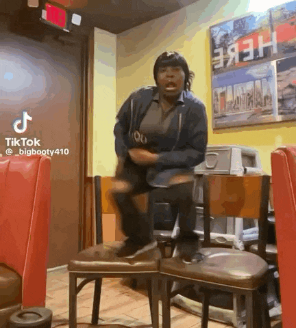 a woman is sitting on a chair in a restaurant while dancing .