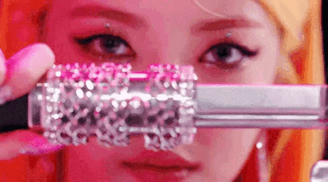 a close up of a woman 's face holding a lipstick .