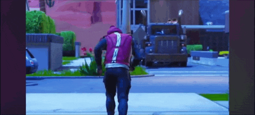 a man in a purple vest is walking down the street in front of a truck .
